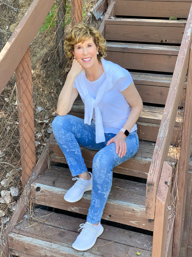 woman wearing whbm floral jeans sitting on wooden steps