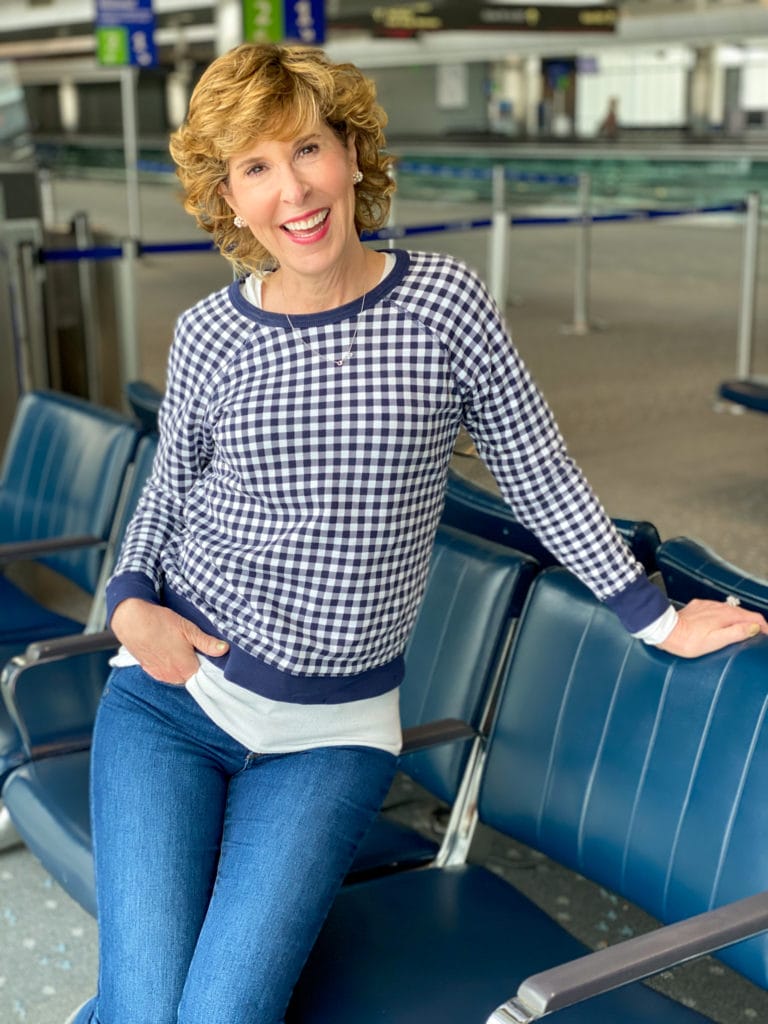 woman wearing draper james navy and white gingham sweatshirt posing in the denver airport