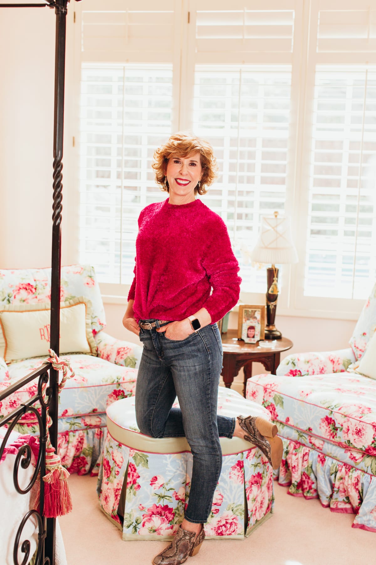 woman in pink fuzzy sweater and jeans posing in her bedroom