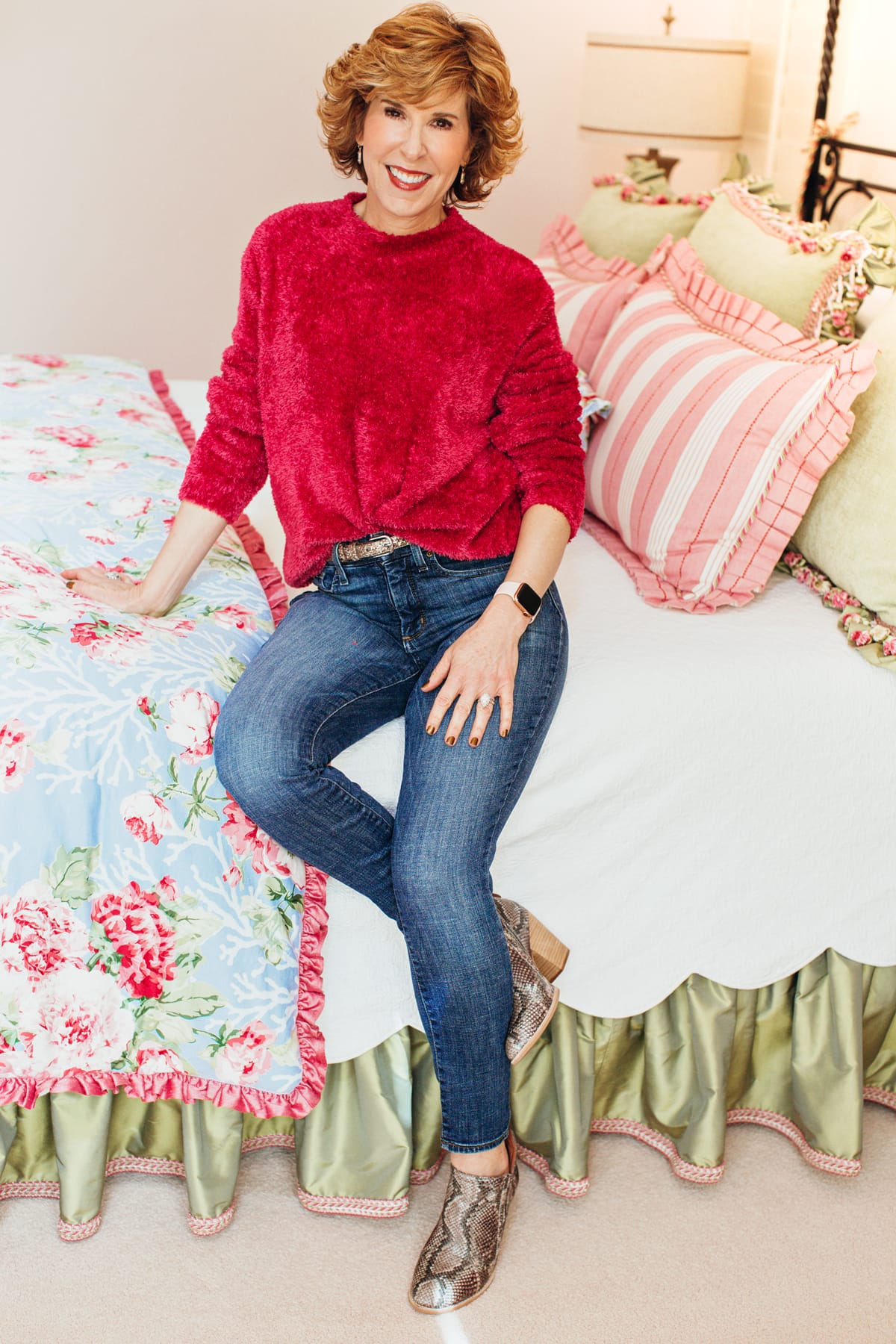 woman in pink fuzzy sweater and jeans posing in her bedroom