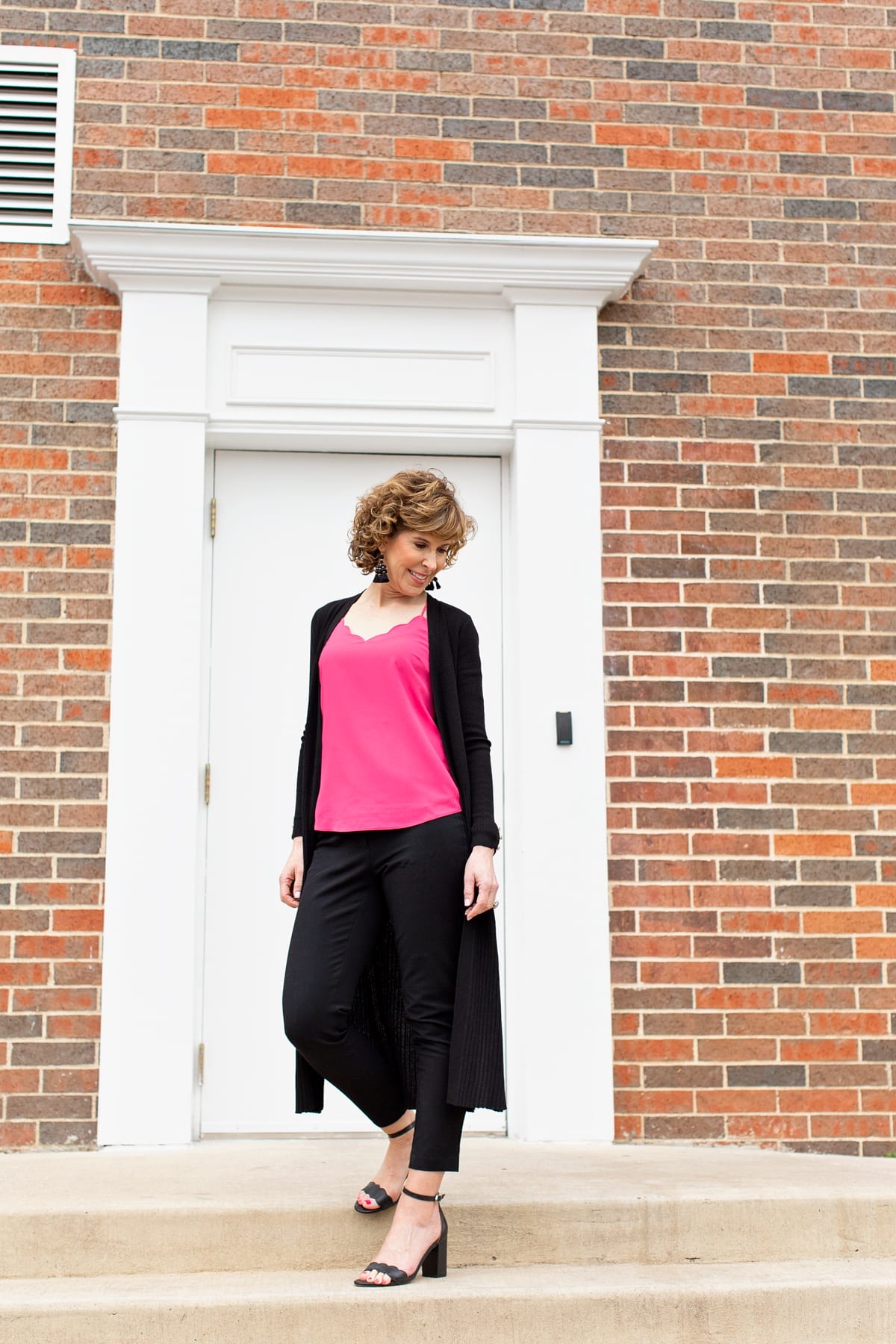 woman standing in front of doorway in pink top with black sweater