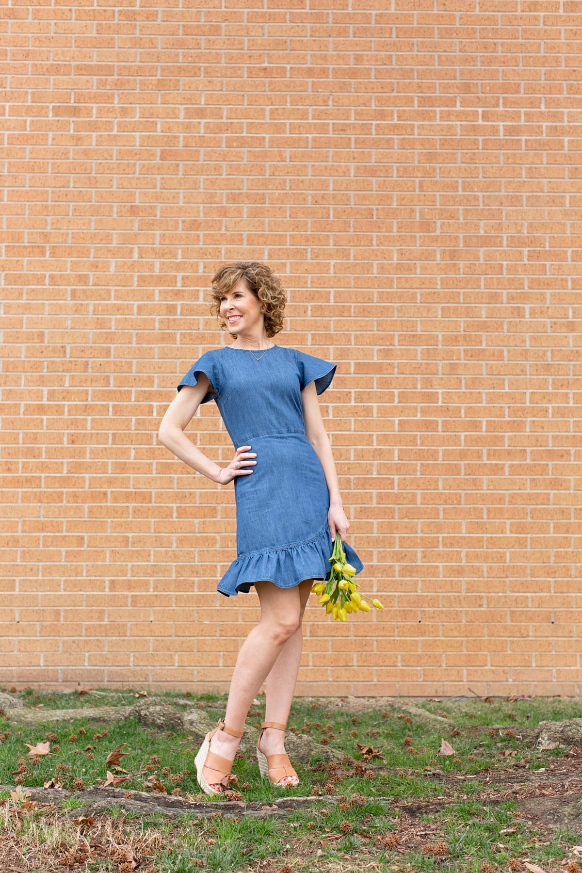 woman in blue dress holding yellow flowers and looking to the side