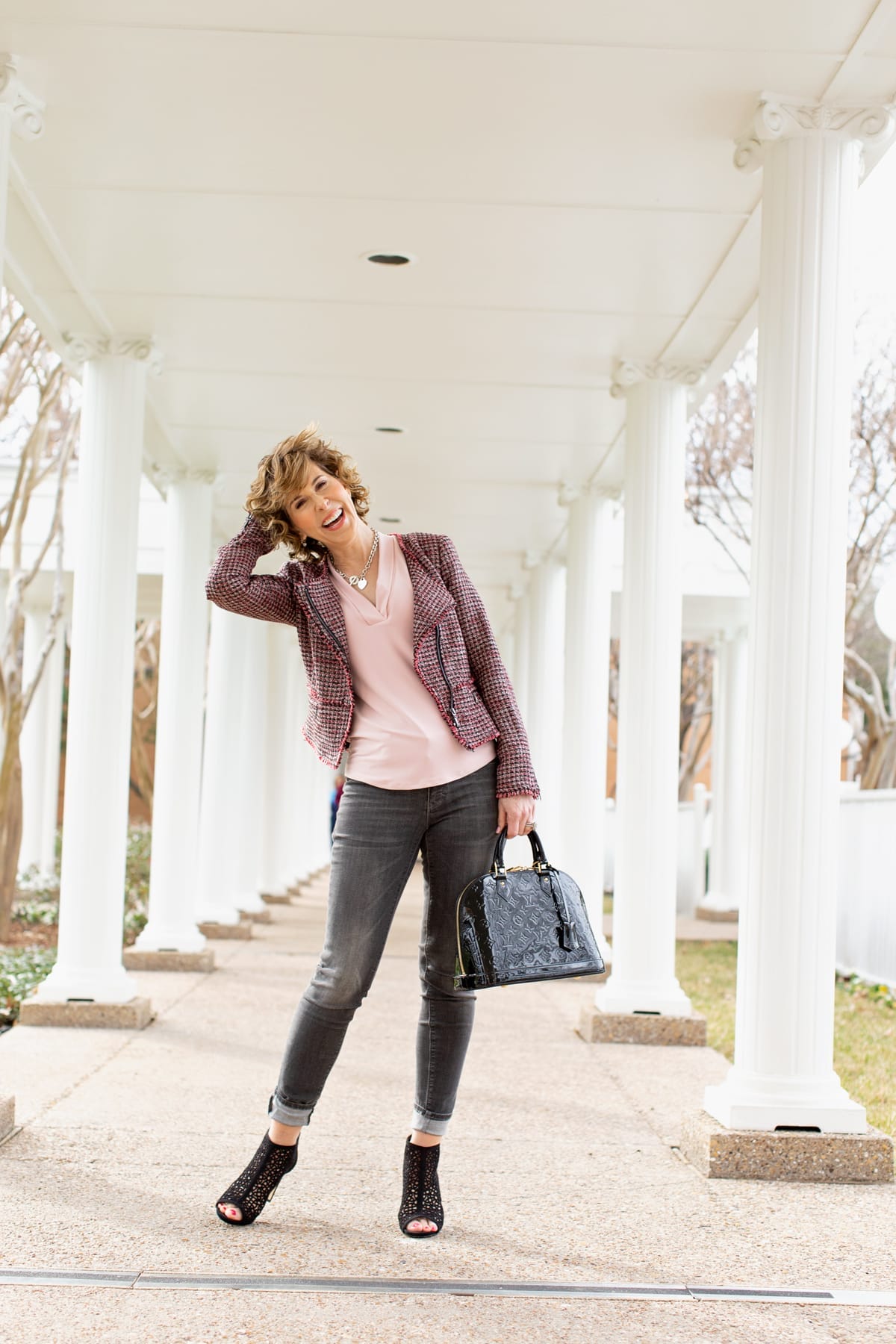 woman in black and pink outfit standing outside among white columns