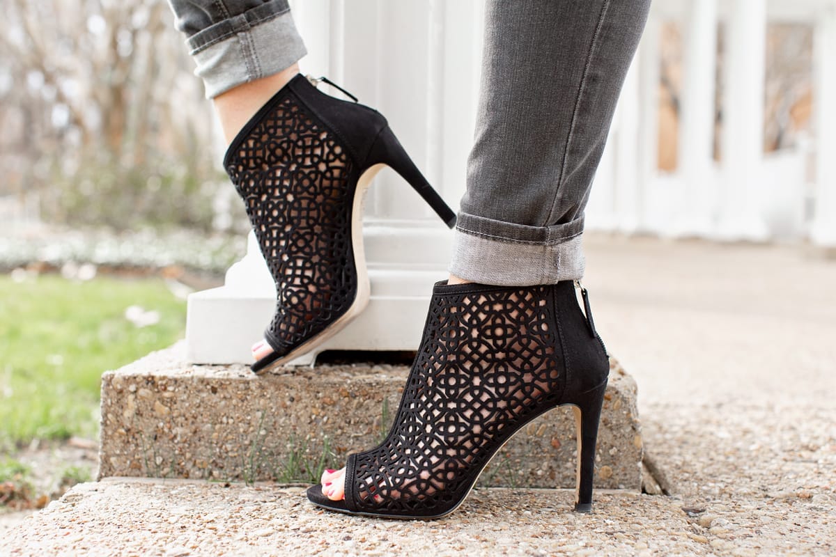 womans feet in black laser cut booties