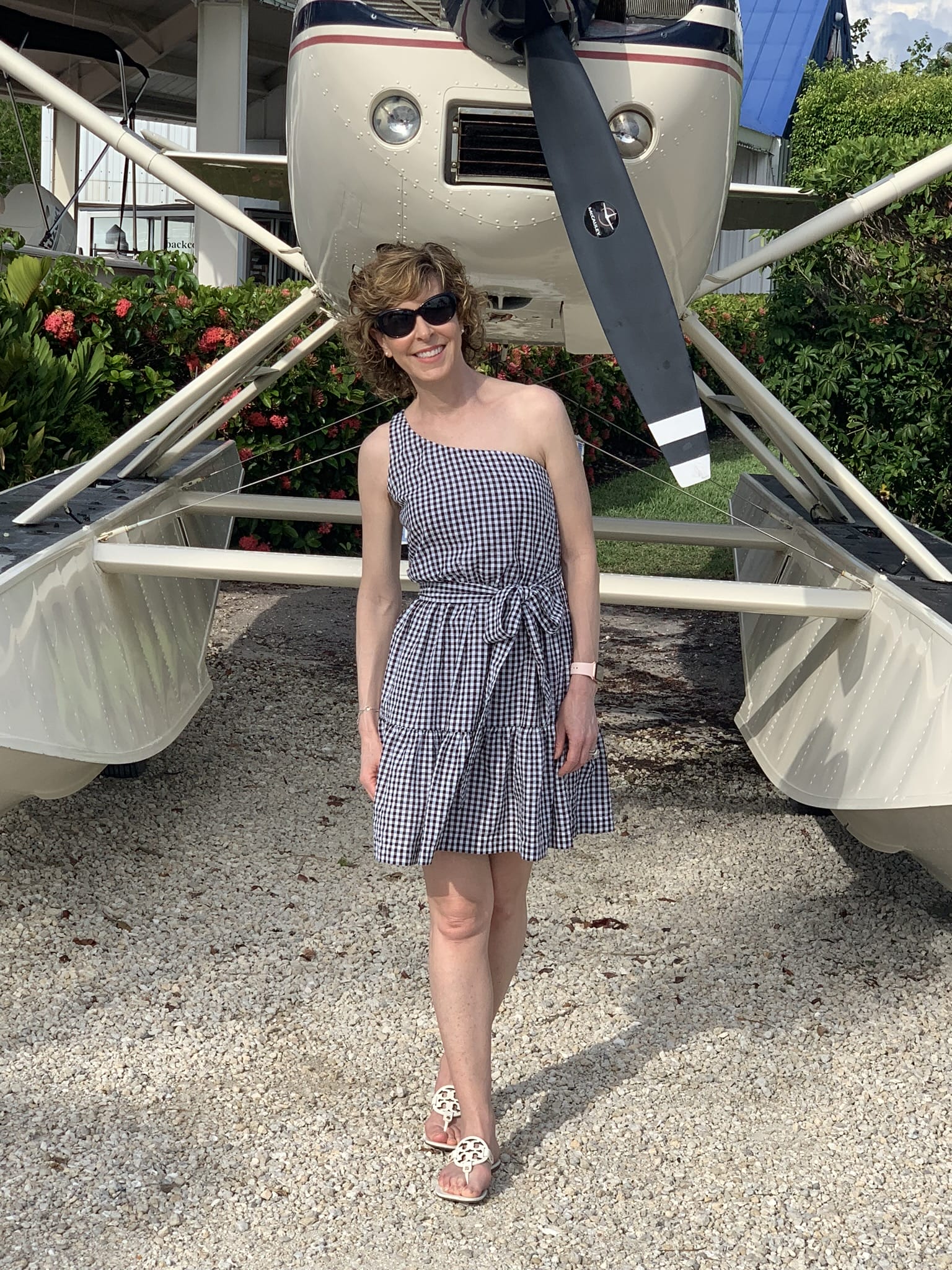 woman in one-shoulder dress posing in front of a plane on sanibel island