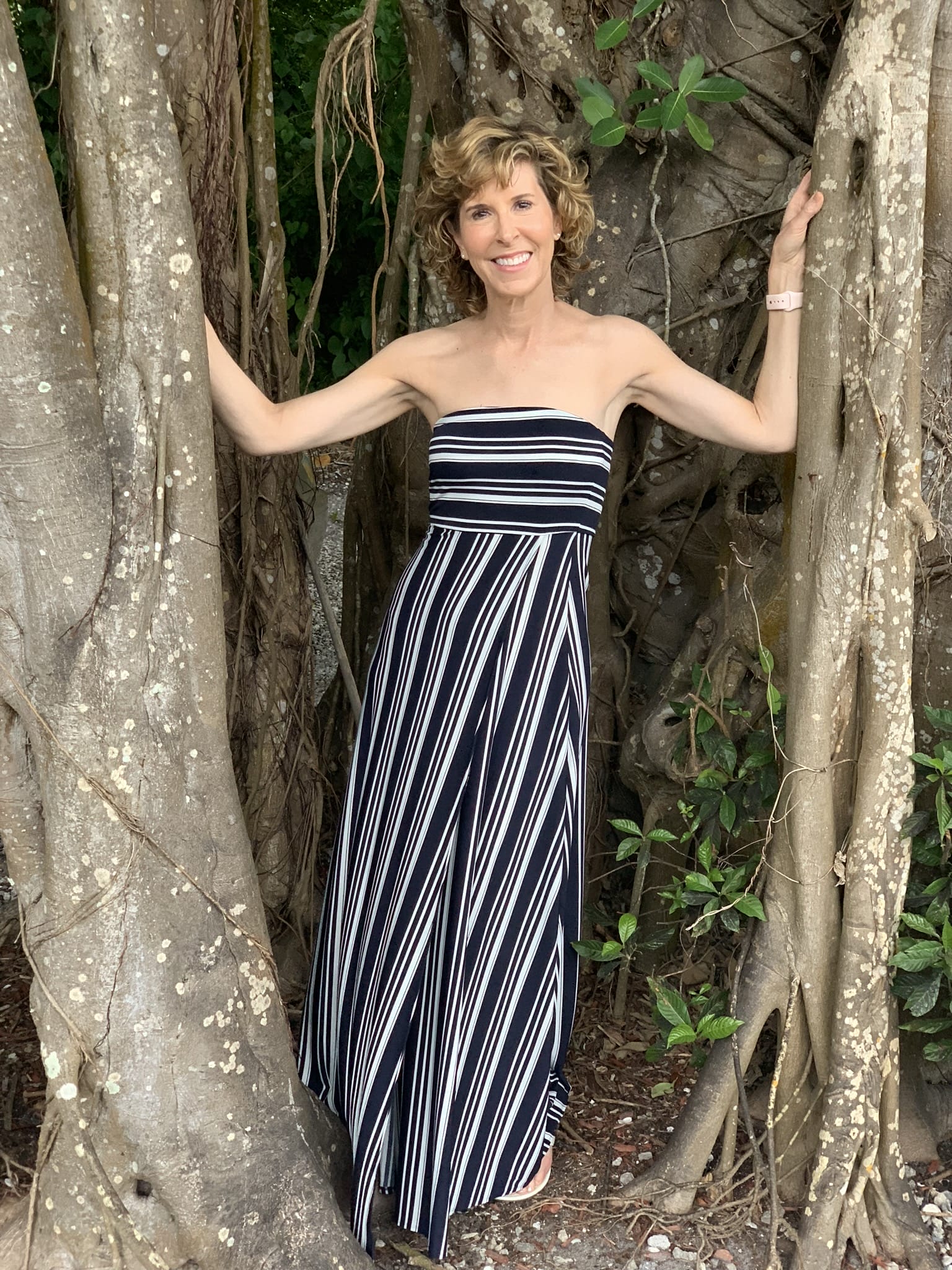 woman wearing blue and white maxi dress standing inside a tree trunk