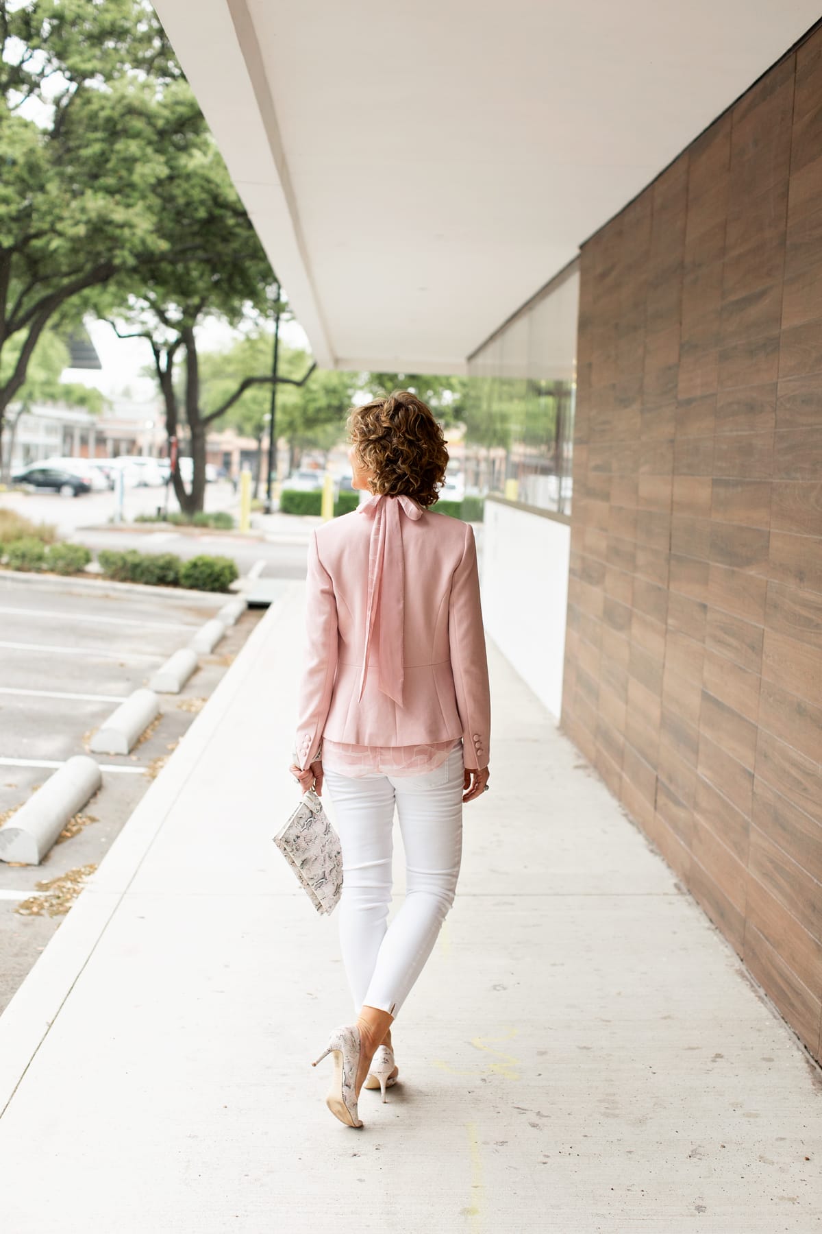 woman wearing pink blazer with a bow down the back