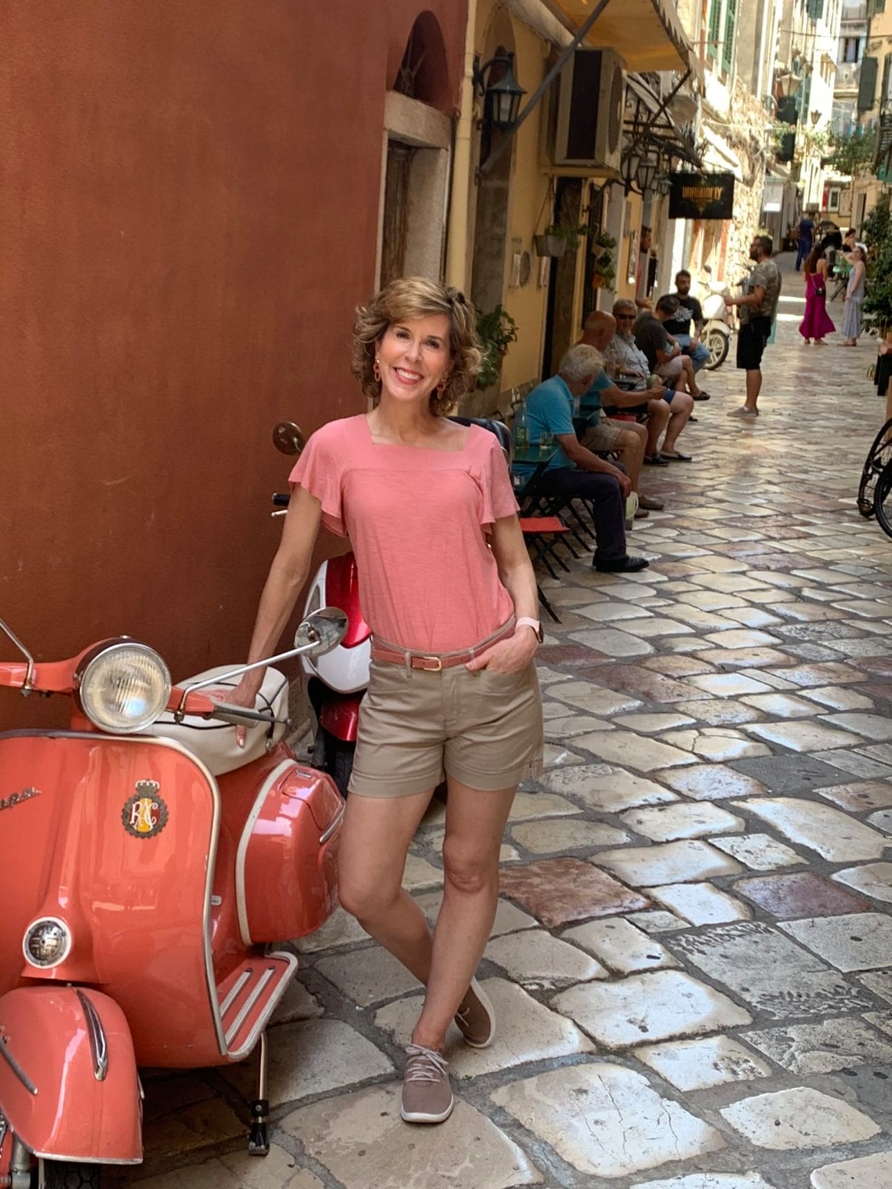 woman standing next to moped in the streets of dubrovnick
