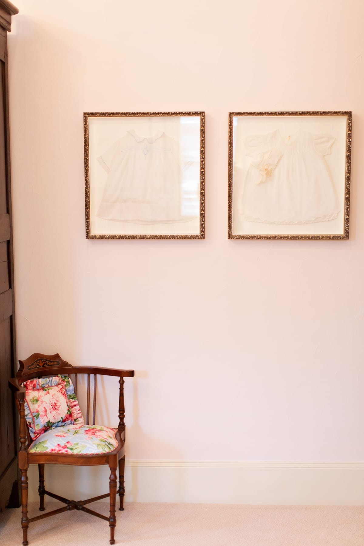 two framed baptismal gowns on the wall of a room