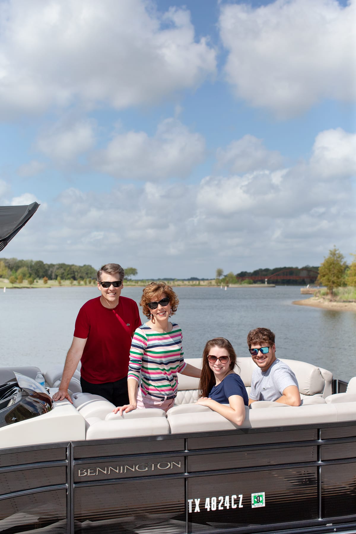 a family of four on a boat looking at camera with a lake behind them