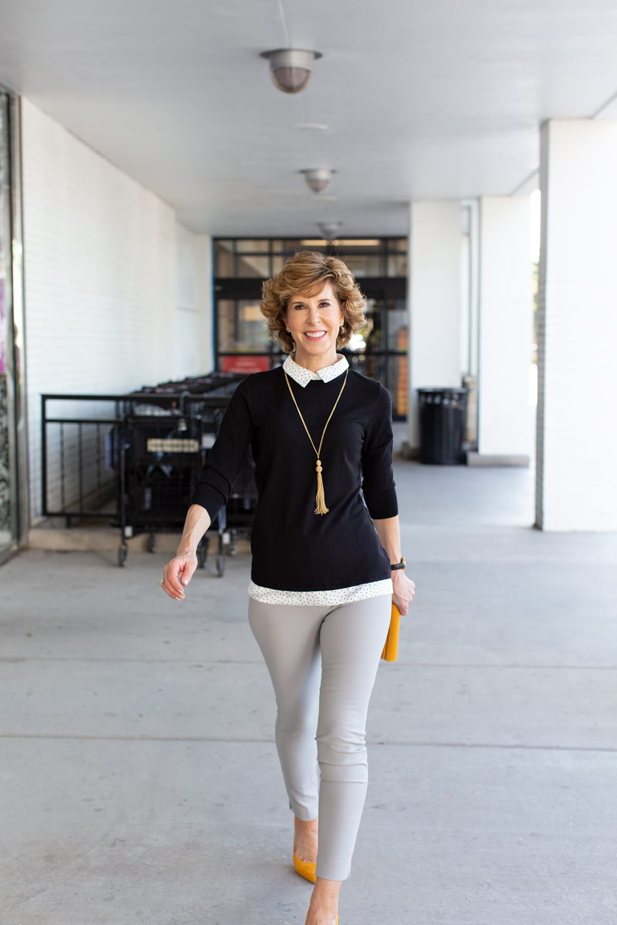 woman in black sweater with yellow shoes and purse walking towards the cameras
