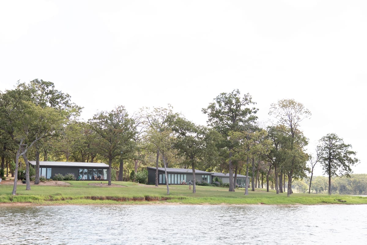 two gray cabins sitting on the side of a lake