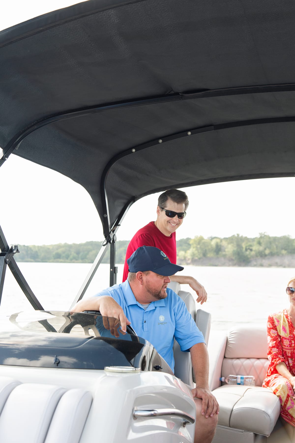 man in blue shirt driving a boat with a man in a red shirt standing behind him