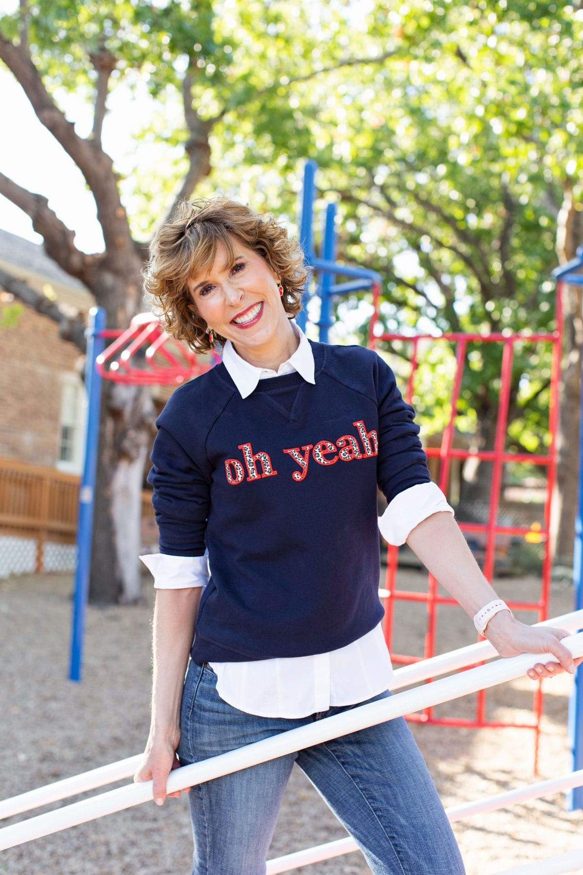 woman wearing blue sweatshirt that says "oh, yeah" in leopard print letters