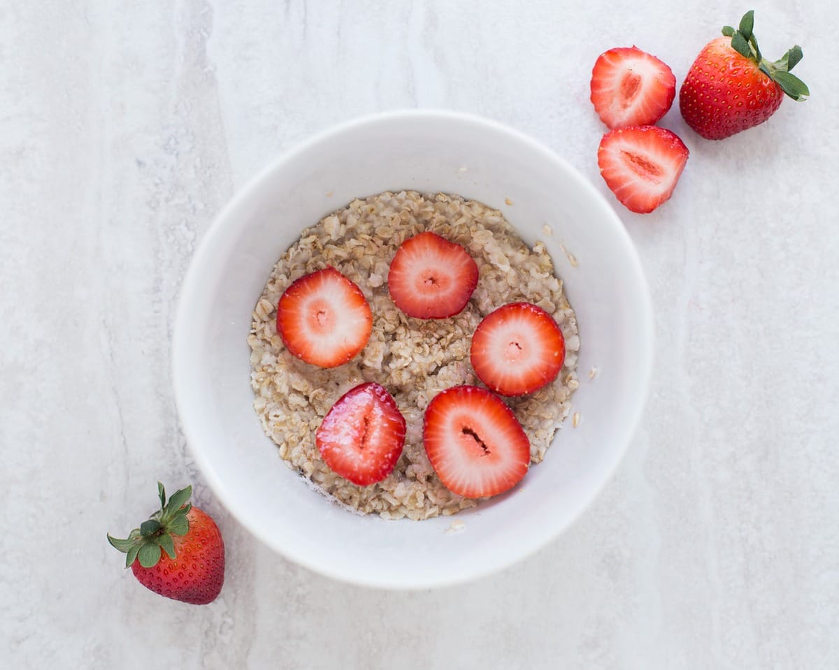 bowl of oatmeal and strawberries on a white table