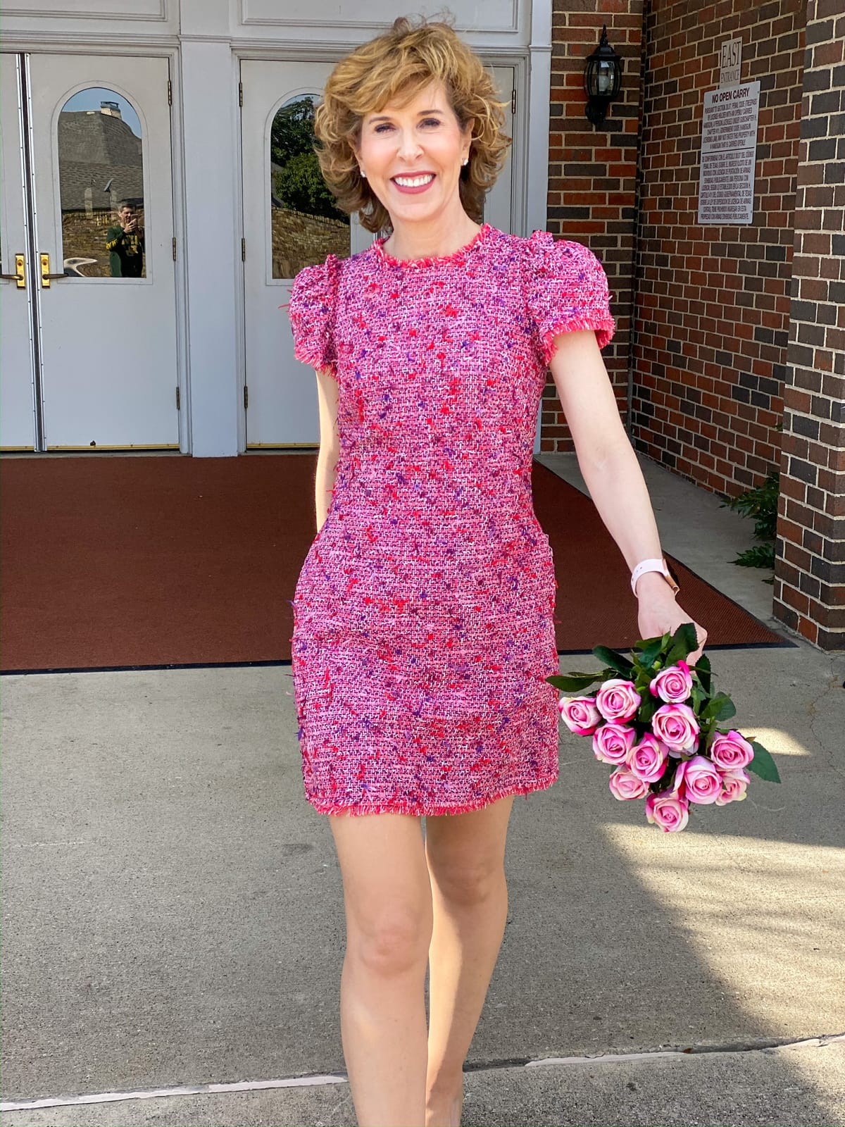 woman in pink tweed dress holding pink roses