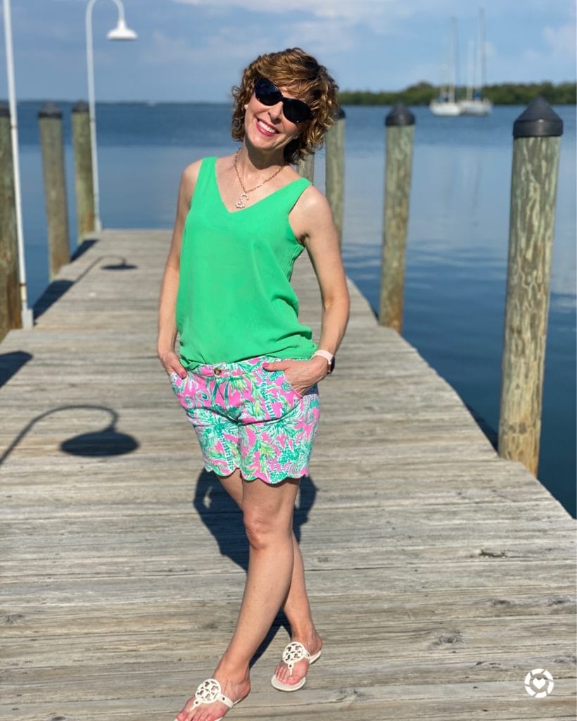 woman wearing green tank top and lilly pulitzer shorts standing on a dock
