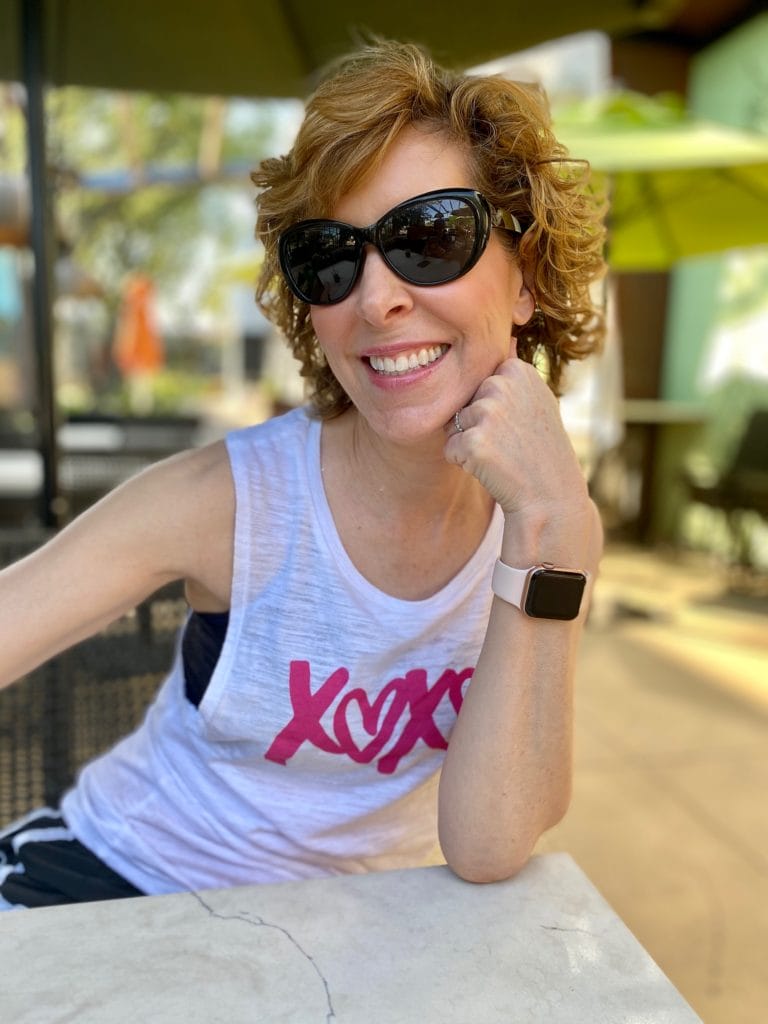 woman wearing xoxo tank top and sunglasses sitting at a table