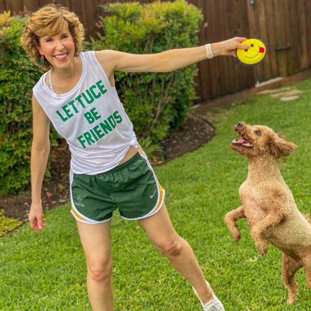 woman wearing lettuce be friends tank top and playing with dog