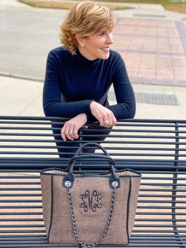 Woman leaning over a park bench with Marley Lilly Monogrammed Charlotte Handbag sitting on the bench in front of her