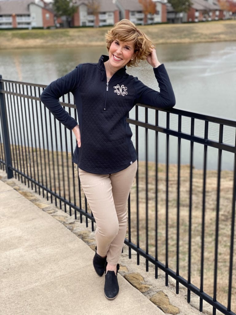 woman wearing marley lilly monogrammed quilted pullover in black posing in front of a lake