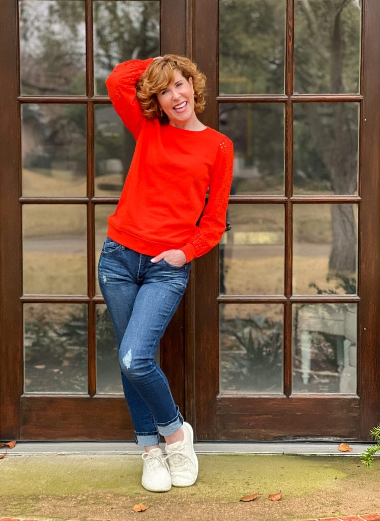 woman wearing talbots Eyelet Sleeve Crewneck Sweatshirt and jeans standing on porch in front of glass doors