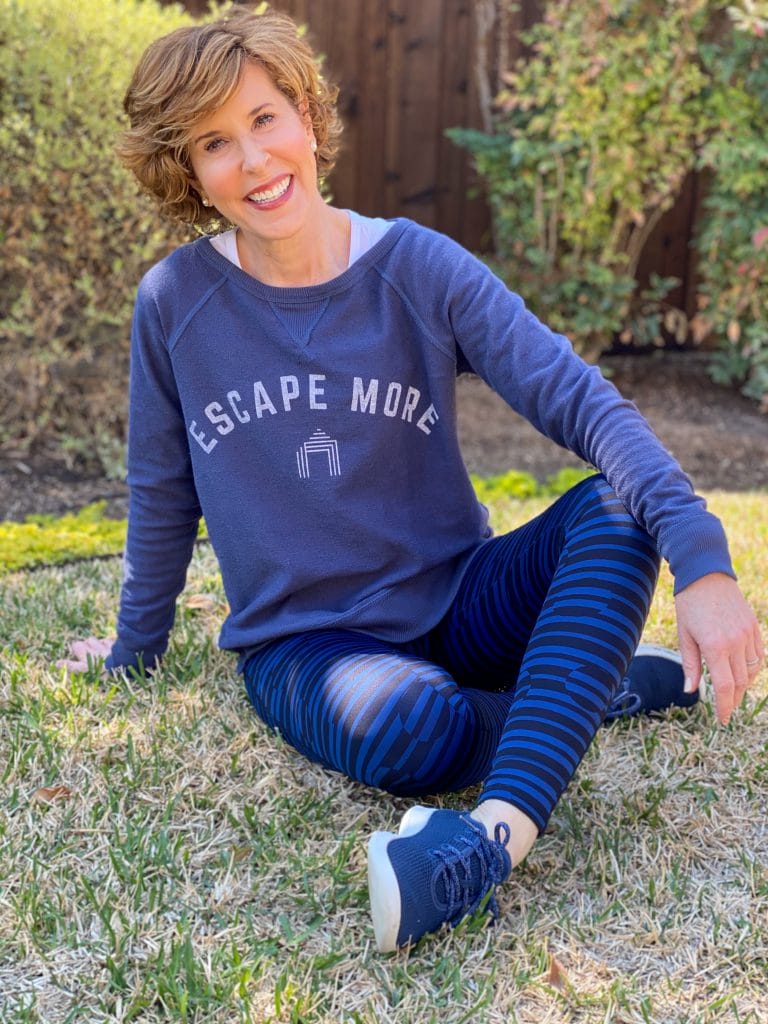 woman over 50 wearing cabana life escape more reversible sweatshirt sitting on the grass