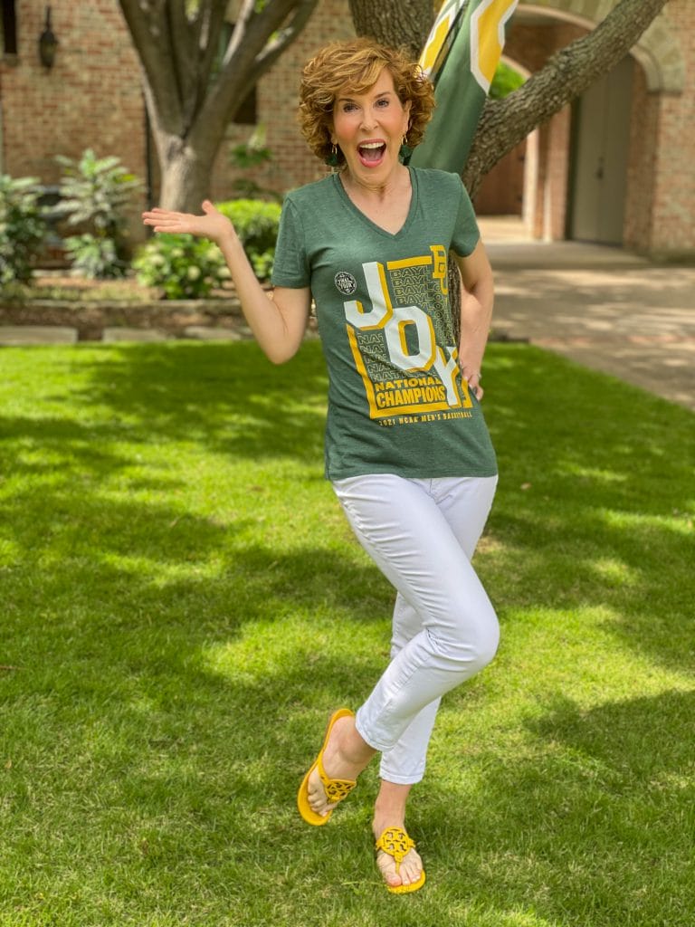 woman wearing green BU JOY tee and white jeans standng in a front yard