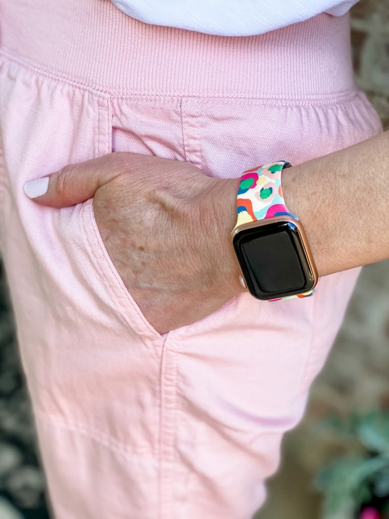 woman with hand in pocket of pink pants showing multicolored apple watch band