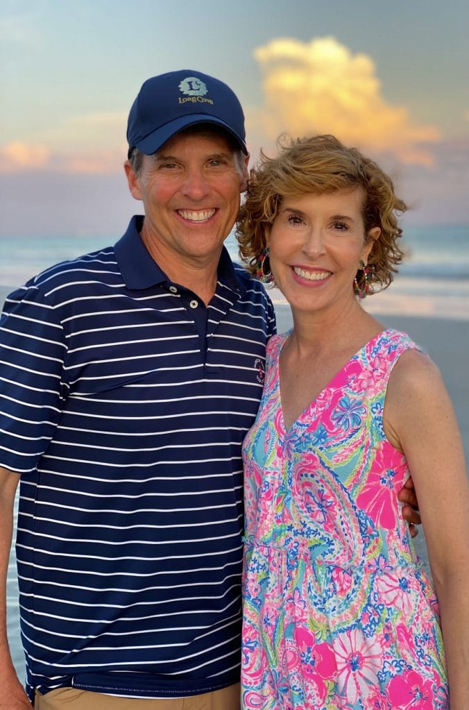 middle age man and woman on beach man wearing striped polo shirt woman wearing lilly pulitzer dress