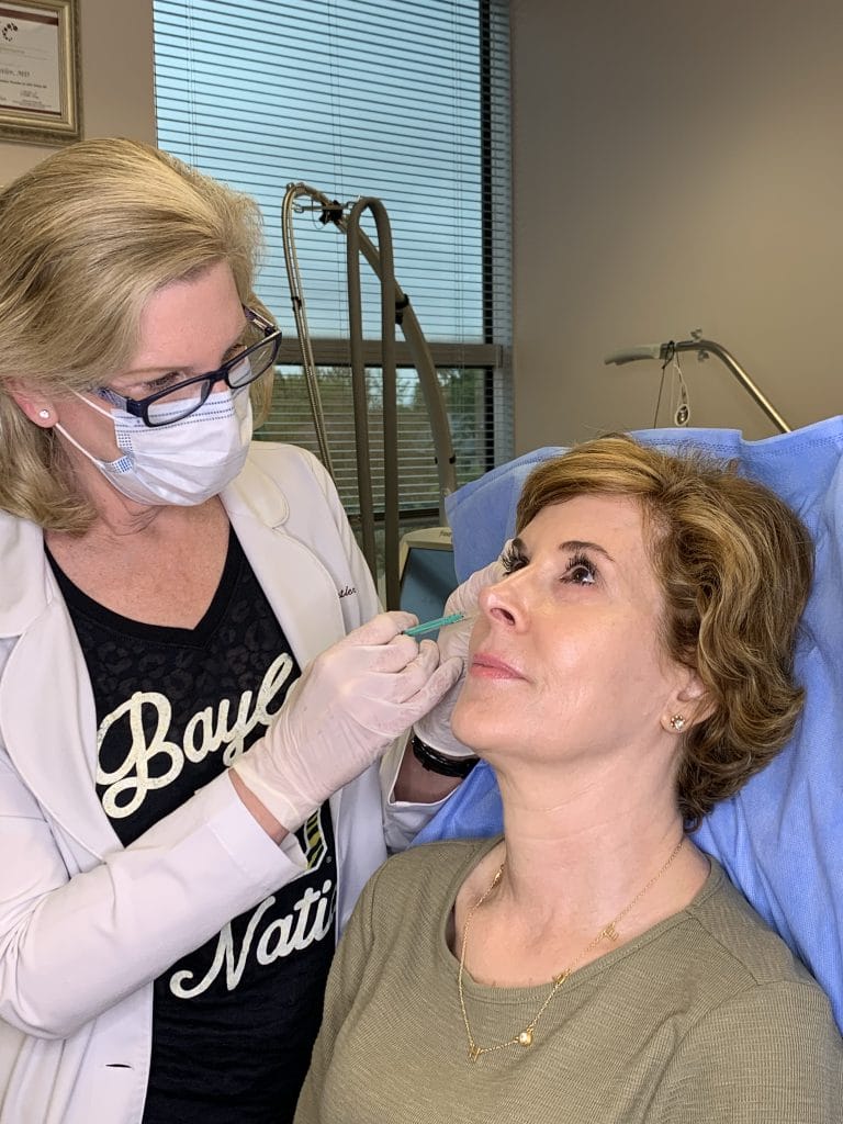 woman over 50 wearing green dress receiving botox injections from dr. lori stetler of dallas center for dermatology and aesthetics