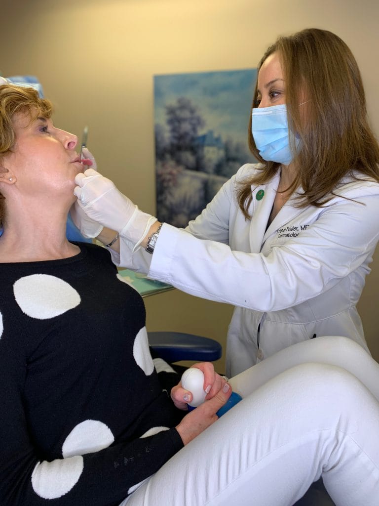 dr kristel polder from the dallas center for dermatology and aesthetics performing dermal fillers on a woman over 50 wearing black and white polka dot sweater