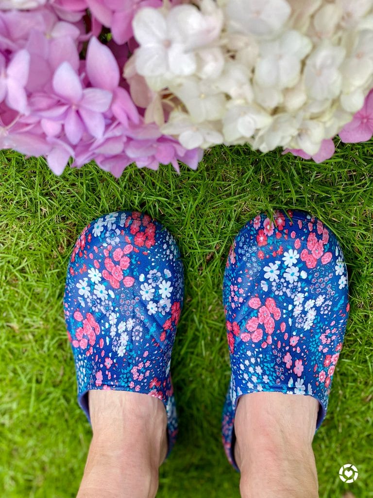 woman wearing easy spirit TGarden clogs standing by hydrangeas