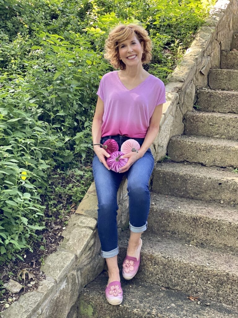 woman wearing WHBM ombre pink jetsetter tee, mott & bow jeans and WHBM espadrille mules and holding 3 pink velvet pumpkins