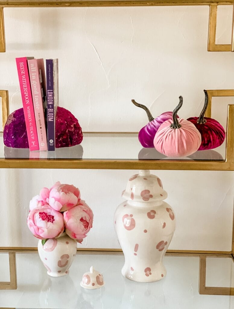 woman's office decor shelves pink pumpkins, pink ginger jar, pink books, pink geode bookends, pink peonies
