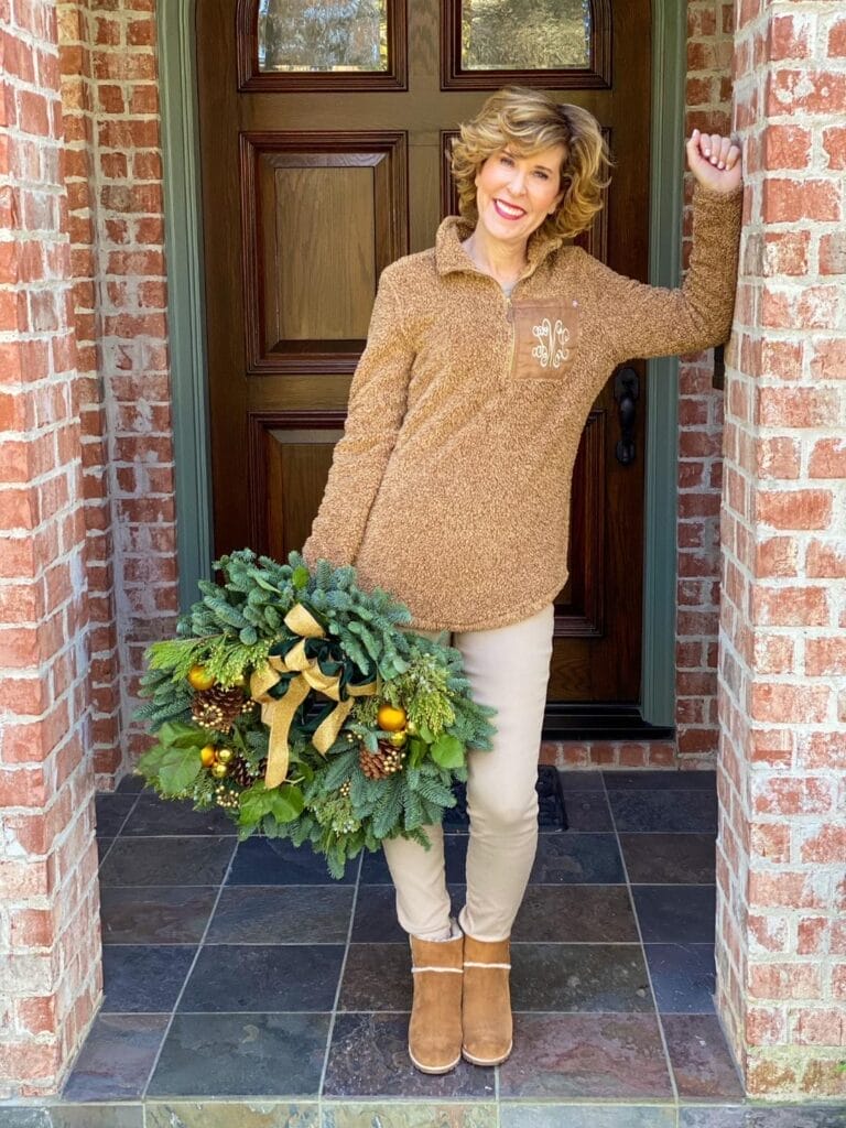 woman standing by her front door holding a wreath