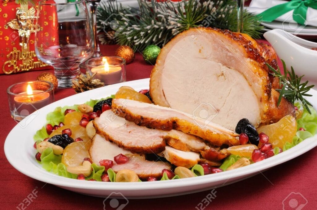 sliced baked turkey ham with fruit garnish on a Christmas table