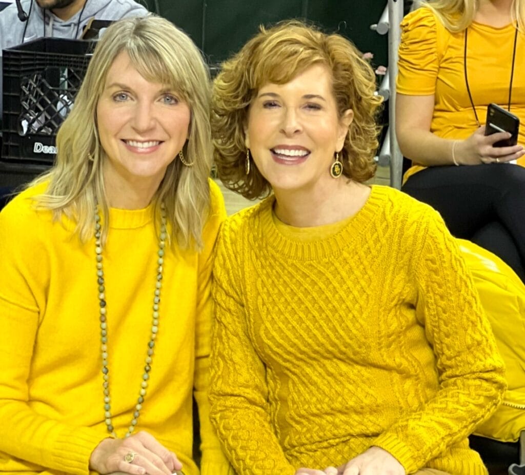 two women over 50 wearing gold tops at a baylor men's basketball game