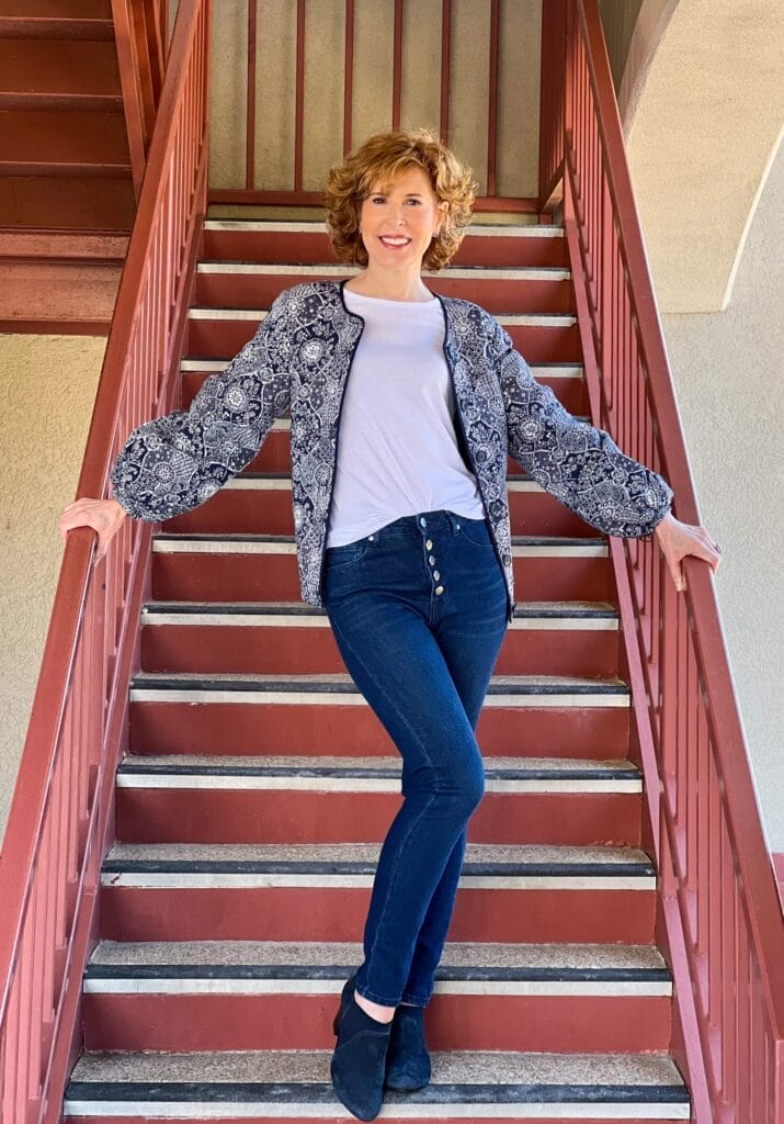 woman over 50 posing on staircase wearing Treasure & Bond Quilted Puff Sleeve Jacket by Nordstrom with a white tee and button fly jeans transition your wardrobe from winter to spring