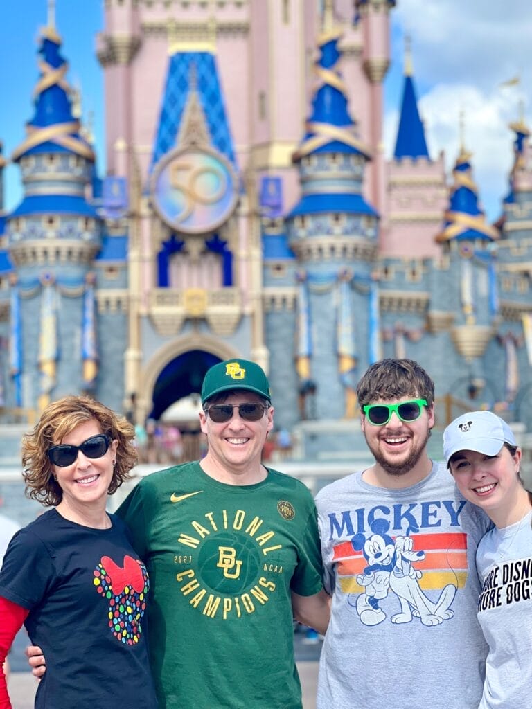 four adults in front of cinderellas castle on a multi-generational disney trip