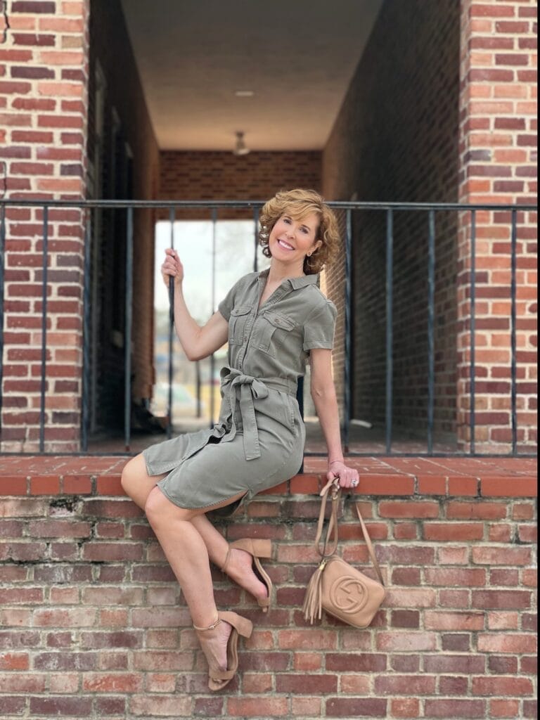 woman over 50 posing in front of a a black wrought iron rail wearing caslon Utility Short Sleeve Shirtdress from nordstrom