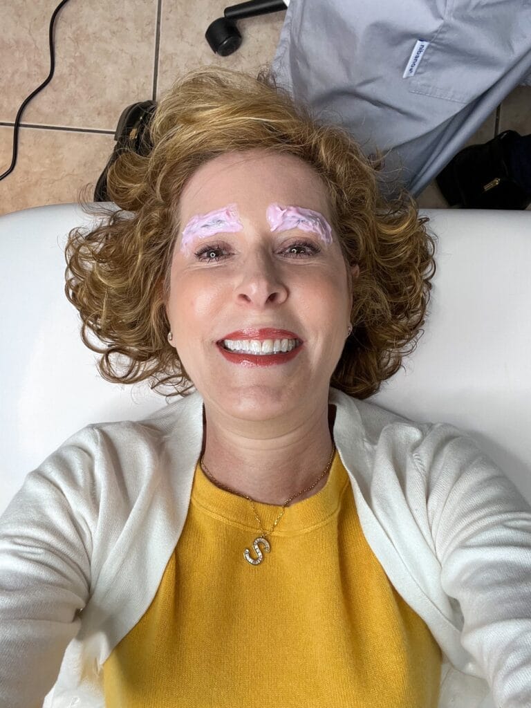 woman over 50 having her brows numbed in preparation for microblading