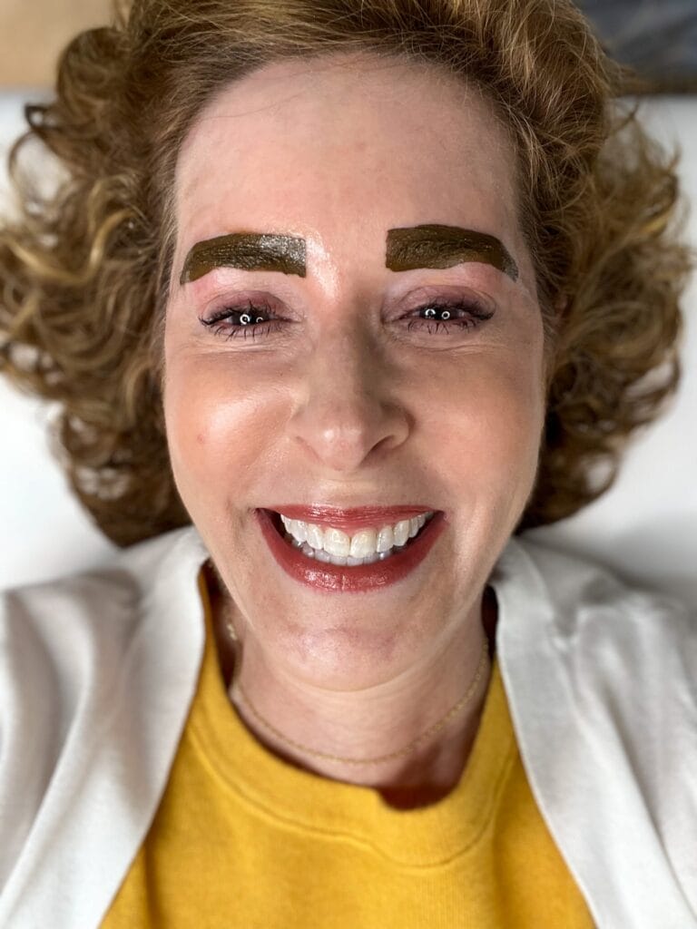 woman smiling during an ink bath after microblading