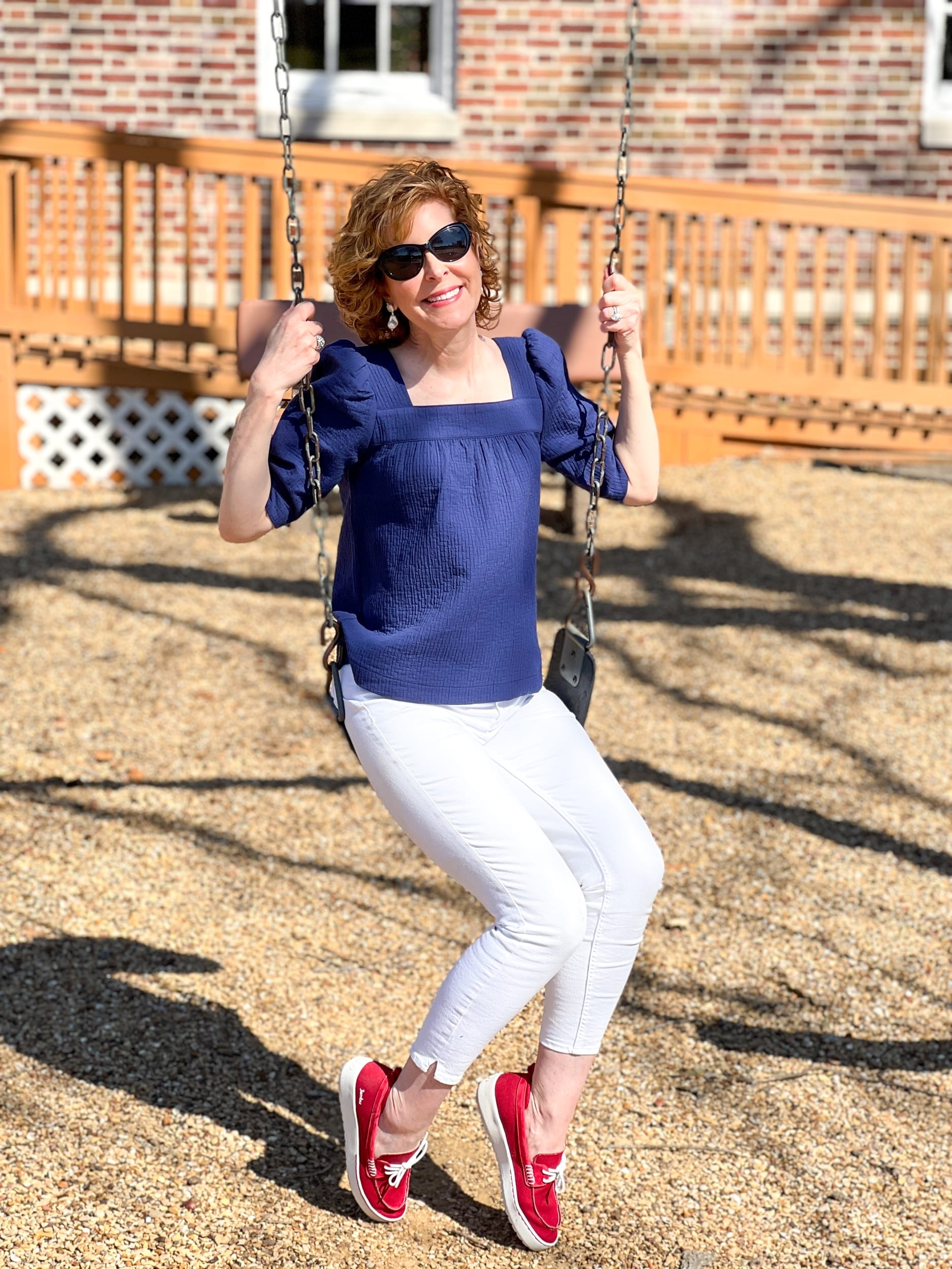 woman over 50 on a swing wearing navy blue Treasure & Bond Textured Babydoll Top with white jeans and red shoes