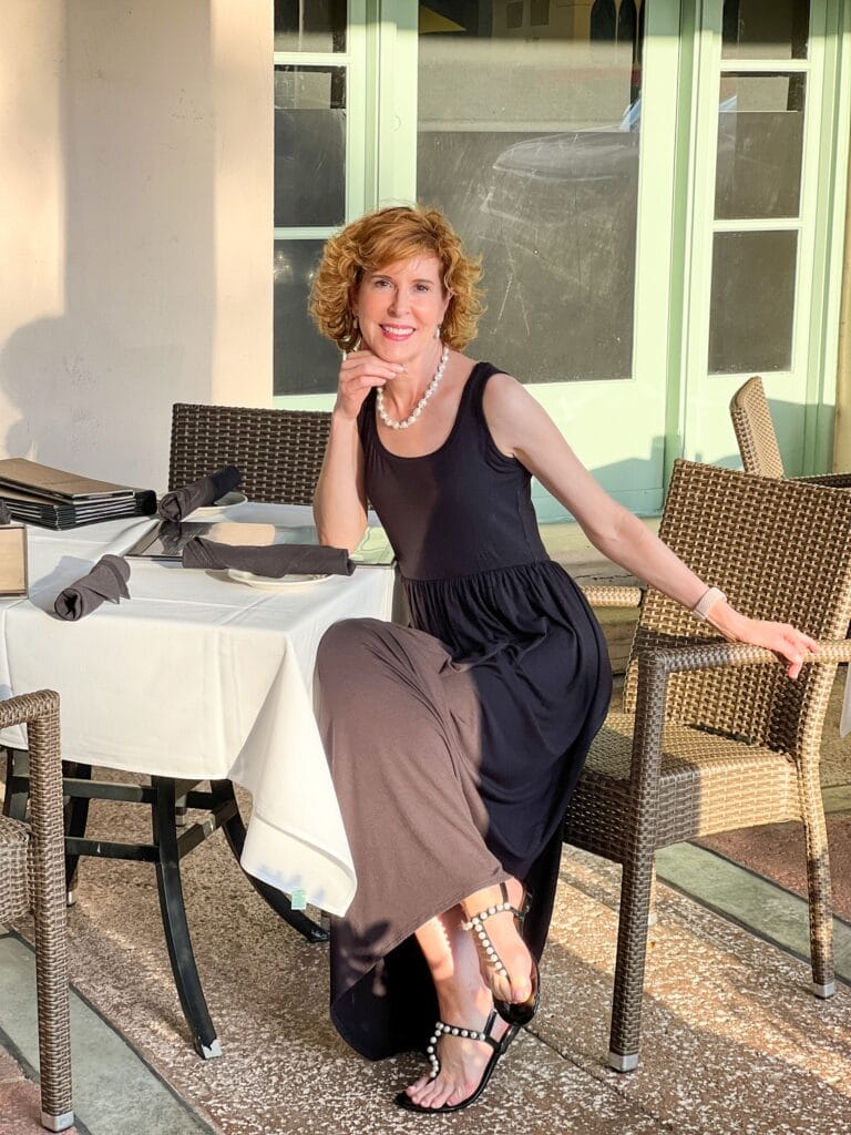 woman sitting at a restaurant patio table wearing black maxi dress