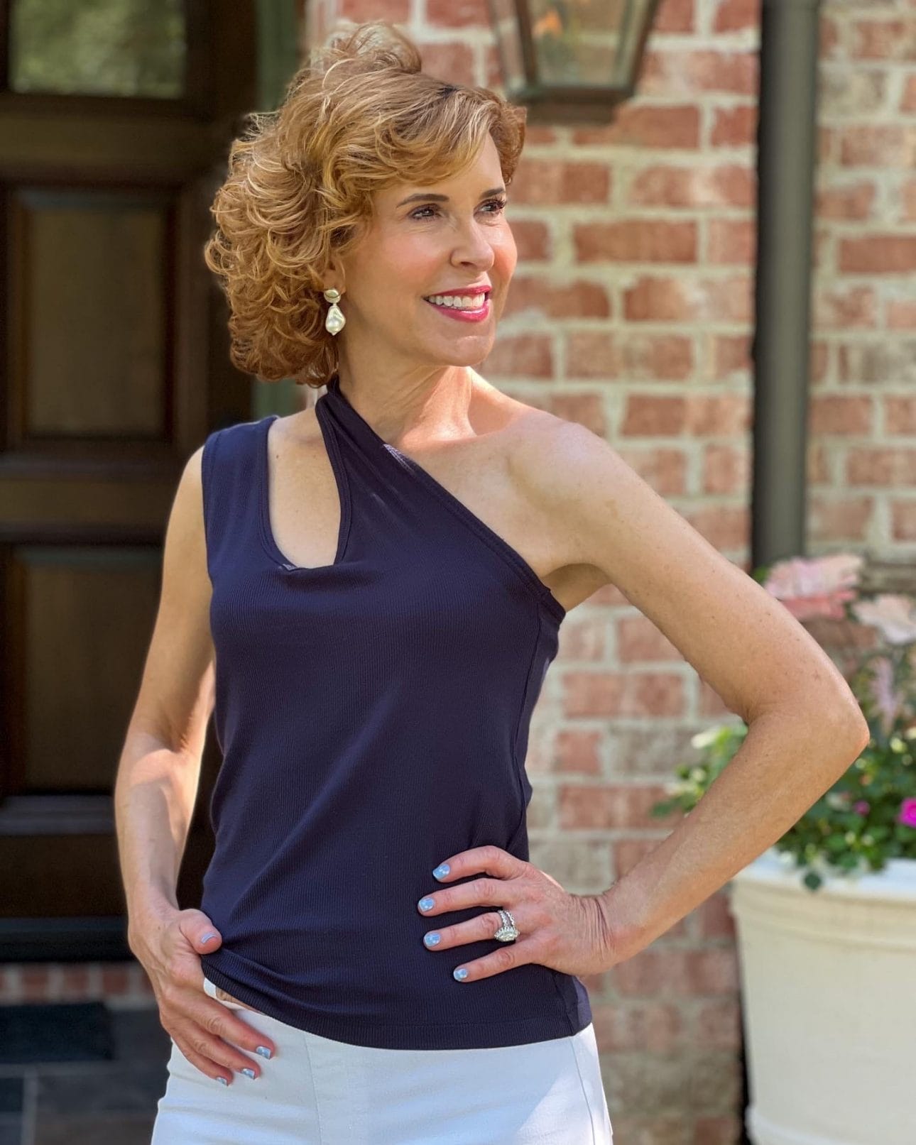 woman over 50 wearing cabi busy tank top one shoulder style from the front