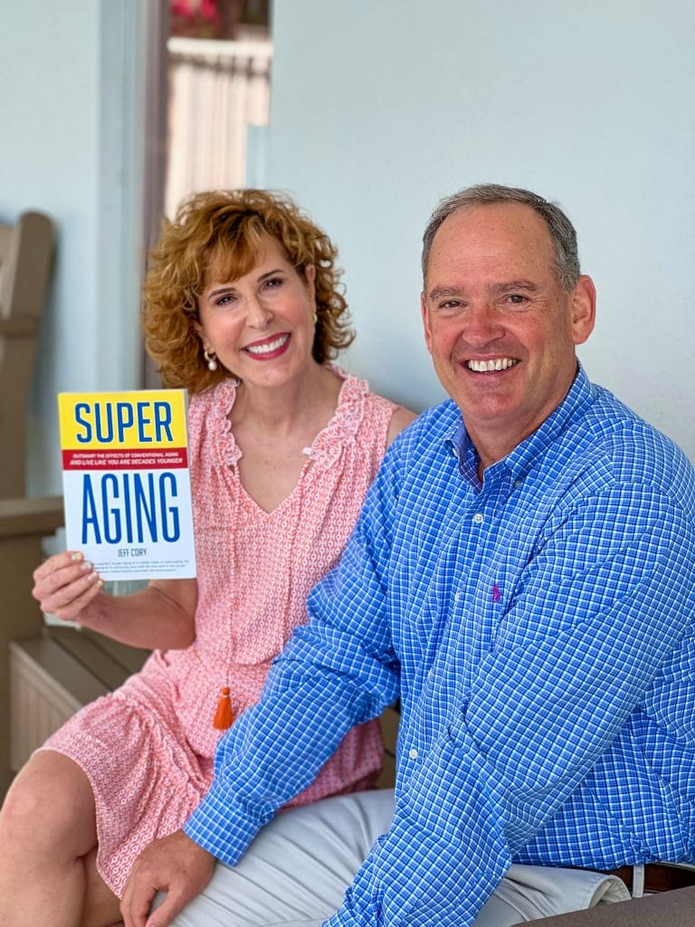woman over 50 holding up book super aging and sitting with book's author