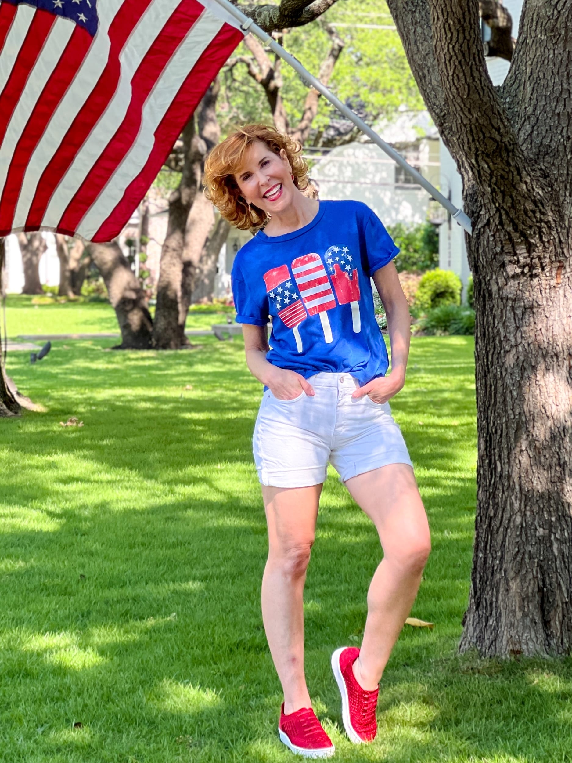 woman wearing patriotic shirt posing by american flag