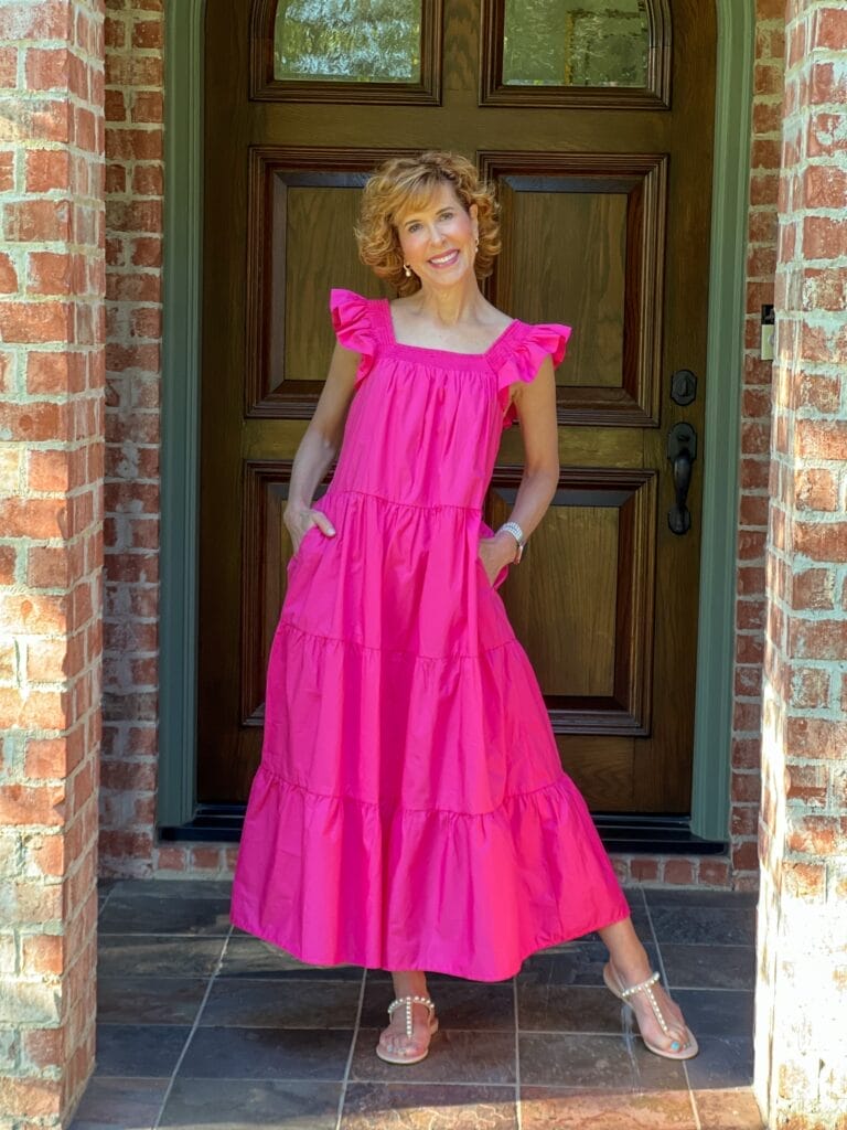 woman standing on front porch wearing pink dress