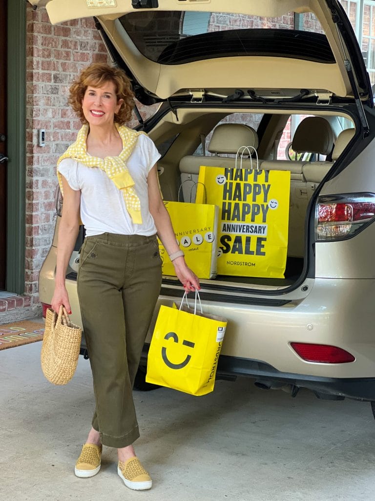 woman over 50 standing by car's trunk filled with nordstrom anniversary sale bags